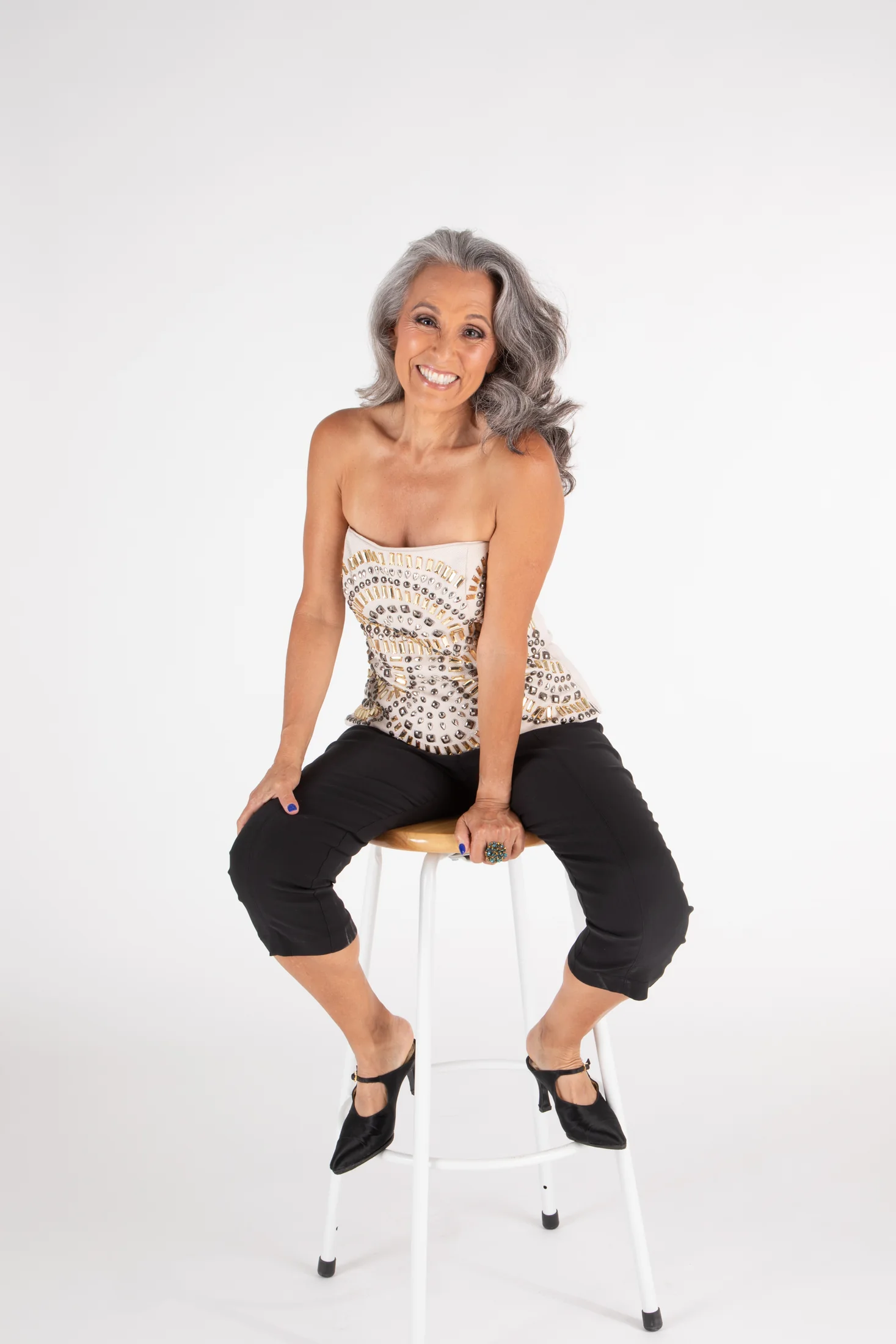 Nicole Jolie seated on a stool in a sparkle top
